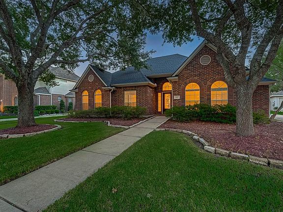 Mature trees frame the entrance to the home.