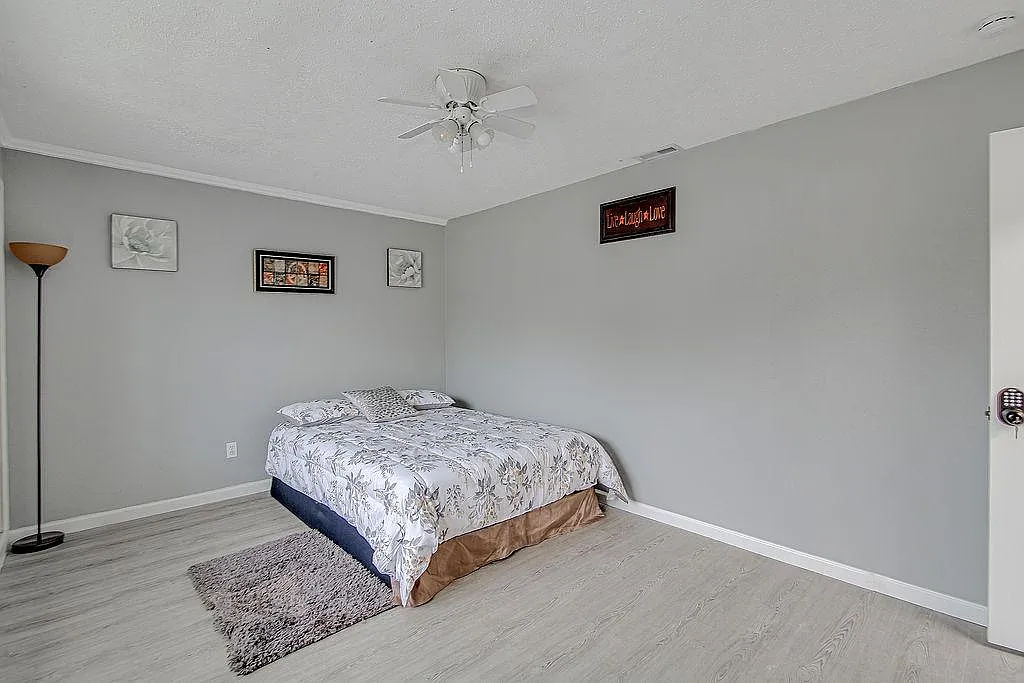 Spacious bedroom with wood-look floors, ceiling fan, and ample room for a full bed plus additional furniture. - Chapel Glen Ter