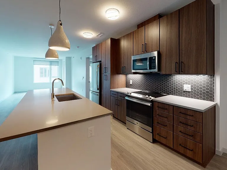 Our alternative option features cozy, chestnut-colored cabinets, paired with a chic, grey designer backsplash and quartz countertops.