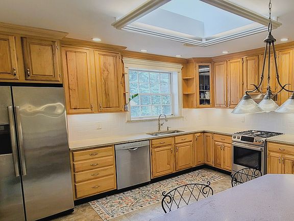 Large chef's kitchen with stainless steel appliances, under-cabinet lighting, marble countertops, in-sink garbage disposal, and plenty of natural light courtesy of the large window and additional skylight.