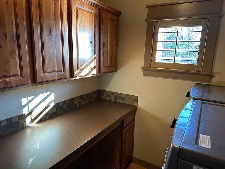 Upstairs laundry room with storage cabinets and countertop workspace