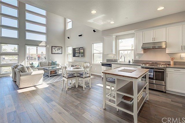 Open floor plan, high ceilings with walls of windows, and wood floors.