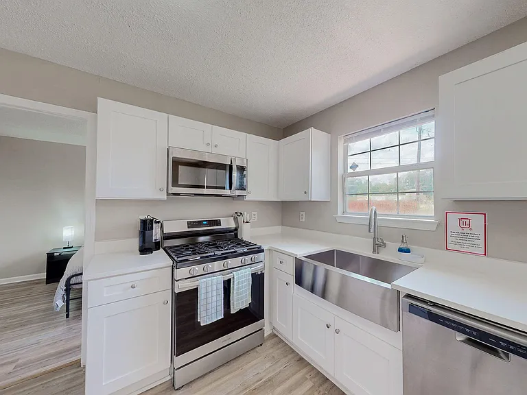 Efficient kitchen with white cabinetry, generous counter space, stainless appliances, and an oversized sink under the window.