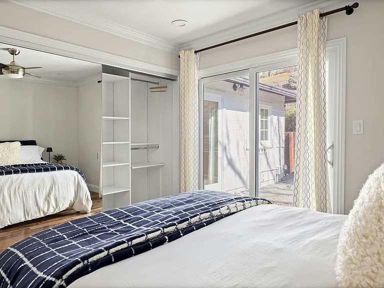 Dual retreat or shared comfort this sunlit bedroom features two cozy sleeping areas, direct outdoor access, and built-in storage, ideal for guests, siblings, or a flexible live-work setup.