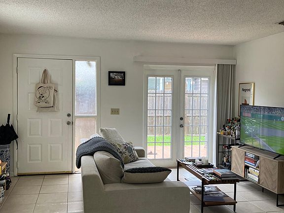 Living area with tile floors and French doors onto brick paver patio and private fenced back yard.
