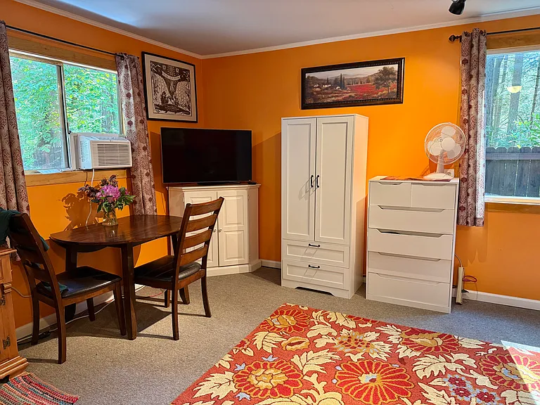 Photo shows smart TV, AC/Fan example of table against wall which opens up floor space. Window on left opens toward the BBQ area outside (see other photos)