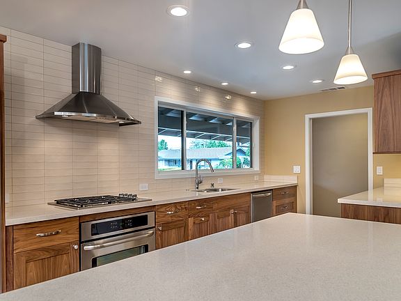 Custom walnut kitchen with large island in open floor plan. Window faces front landscaping.