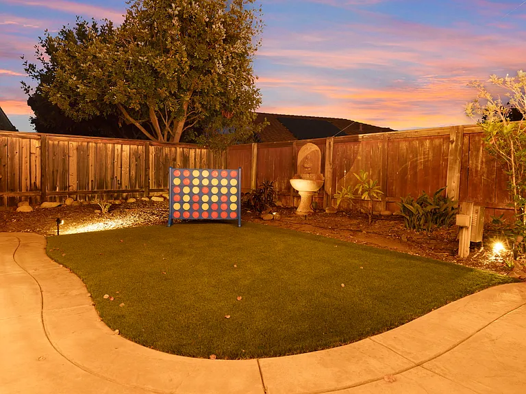A large Connect Four game on the backyard turf offers endless fun. The vibrant, oversized game board stands out against the green grass, inviting players to strategize and compete. Perfect for family gatherings and friendly outdoor challenges.