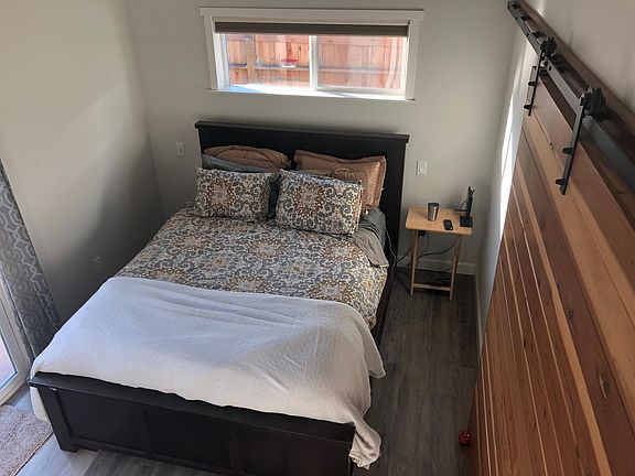 Bedroom with barn door and sliding glass door entrance to patio.