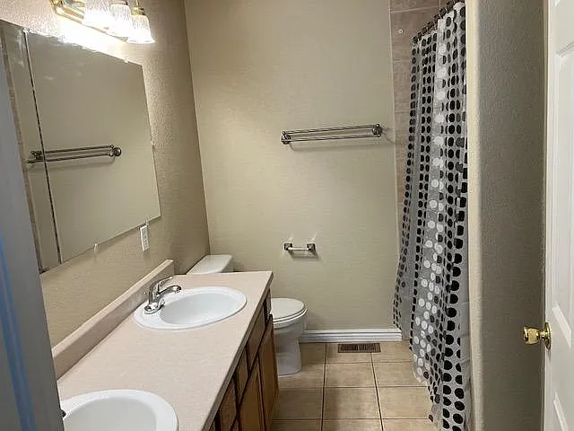 Full bathroom with long vanity and ample counter space, plus a tub/shower combo and convenient towel storage.