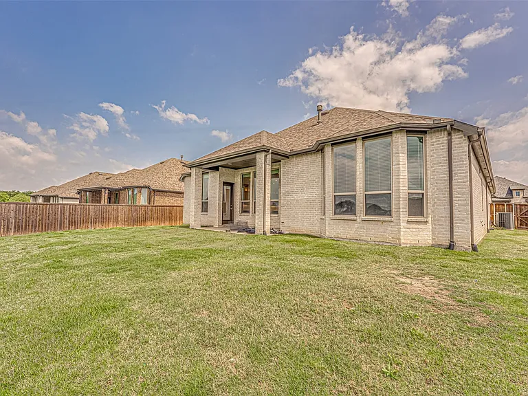 Expansive backyard featuring a lush lawn, a privacy fence, and a covered patio area
