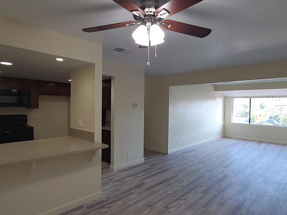View of dining room and living room layout. Front door entrance is on the right. Bay window view of hills beyond the complex.