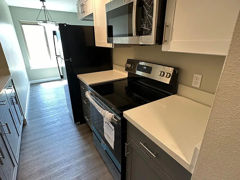 Kitchen with new quartz countertop and cabinets. Dishwasher, stove range, microwave, and big size refrigerator