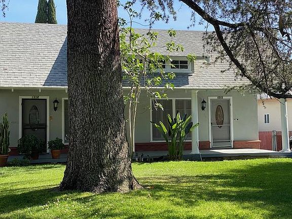 Curbside view with trees and automatic sprinklers.