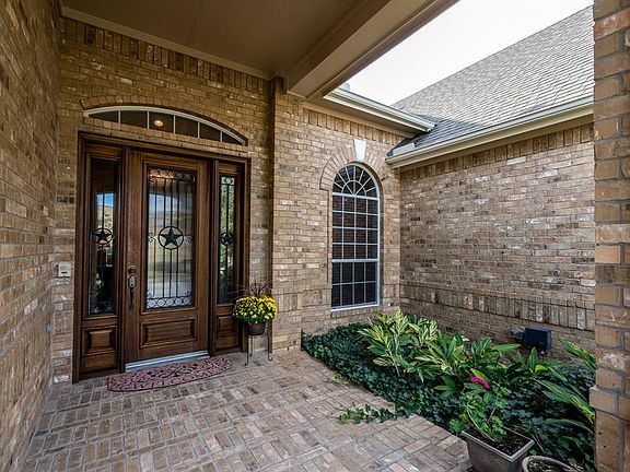 Pretty as a picture! Image creating another sitting area right at the front entry! Enjoy the foliage under this covered brick front porch on a misty morning!