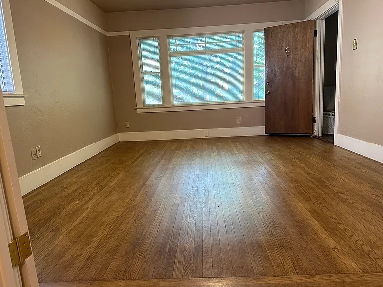 View from dining room, looking toward picture windows in the living room. Front entrance to stairwell. This apartment has three ceiling fans.