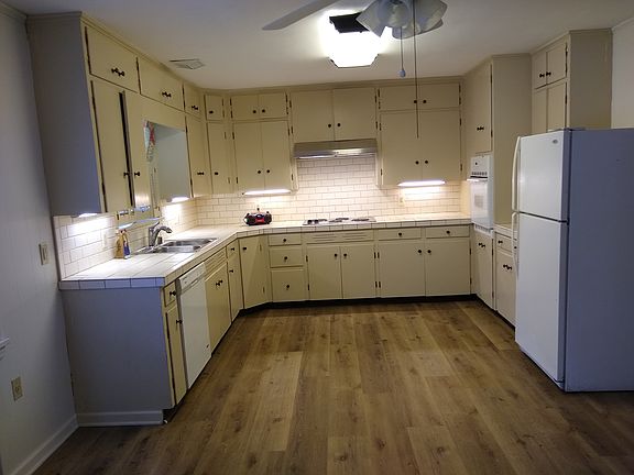 Center view of well-lit kitchen and potential small dining area with lighted ceiling fan.