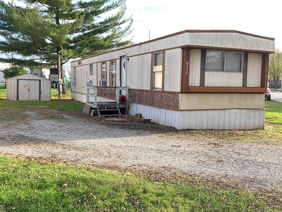 Front of mobile home, driveway and storage shed.