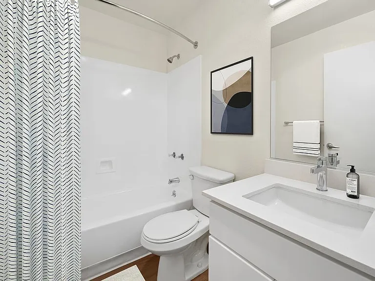 Renovated Package I bath with white cabinetry, white quartz countertops, and hard surface flooring