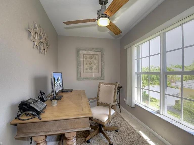 Home office - A tranquil home office / den with large windows and plenty of natural light makes remote work a breeze. The space is tastefully furnished with coastal decor, a wood desk, and high-speed Wi-Fi.