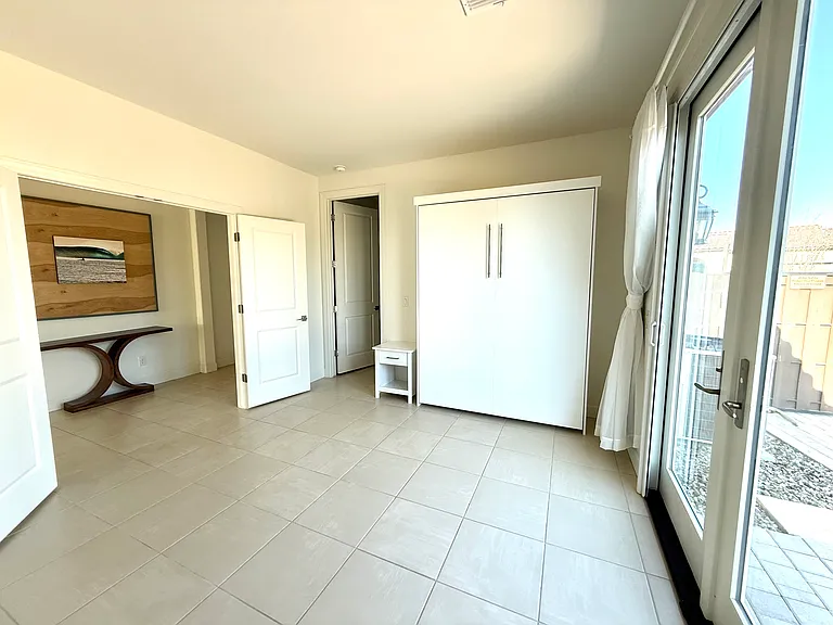 Bedroom or casita living space with separate side entrance, murphy bed, and closet with built in desk.