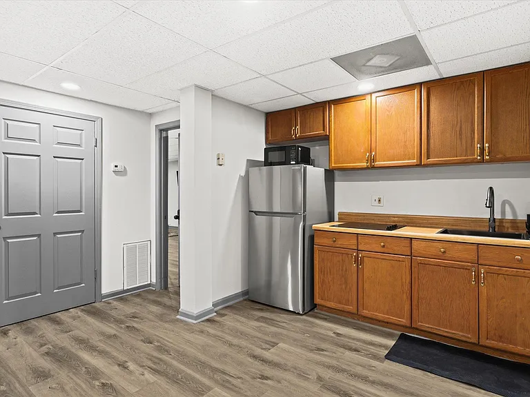 Basement kitchen equipped with electric stovetop, fridge, microwave, ands