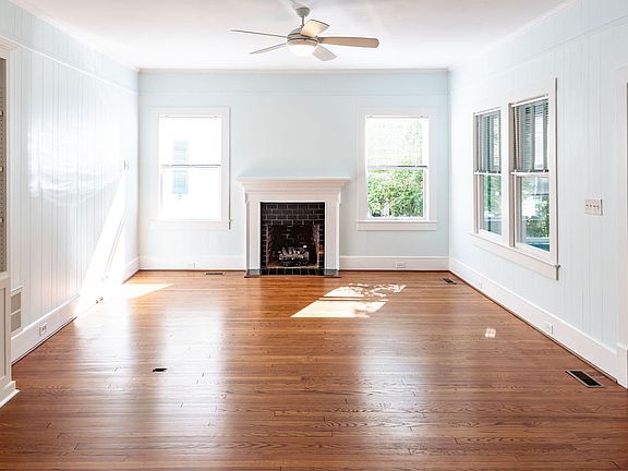 Sunlit interior with open floor plan, built-in bookcase and fireplace.
