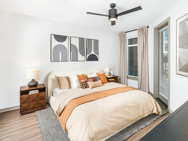 Spacious bedroom showcases wood-style flooring, modern ceiling fan, and large windows for abundant natural light.