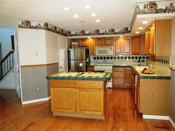Custom ceramic tile design on counter tops and back splash. There's an opening above the sink that looks into the hot tub room. 
