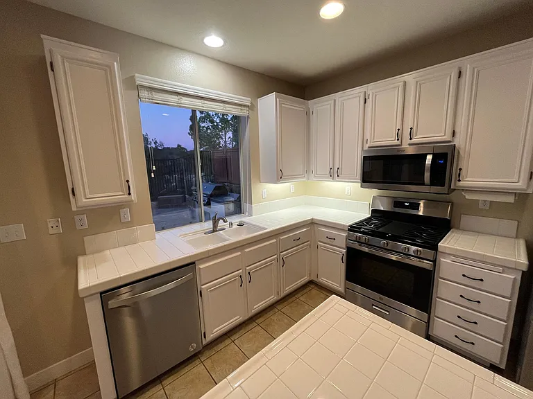 Upgraded stainless steel kitchen appliances including fridge, dishwasher, gas stove, and microwave range
