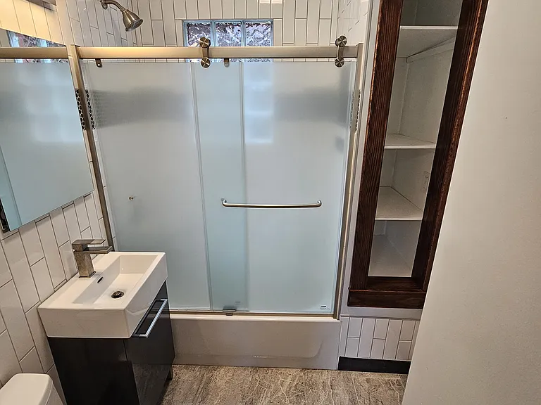Sliding shower door and storage area for towels and other bathroom supplies - perfect for storage bins or baskets.