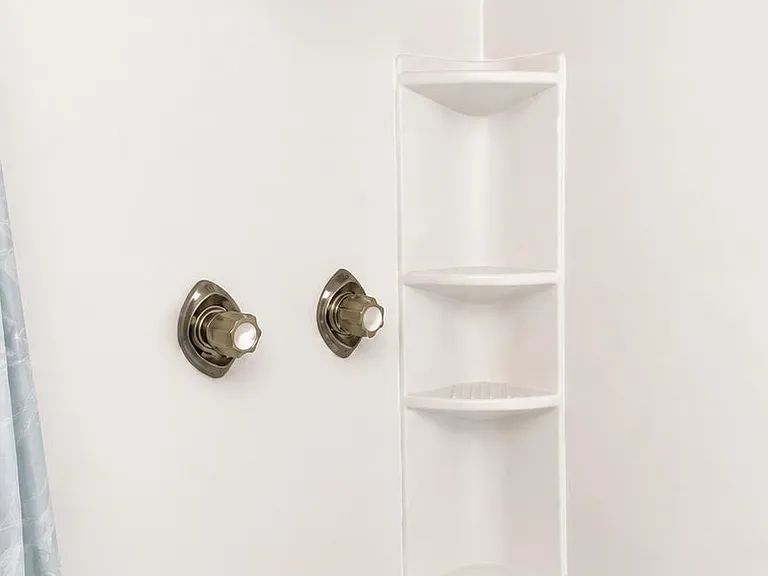 Tub/shower combo with adjustable showerhead, dual controls, and built-in corner shelves for convenient storage.