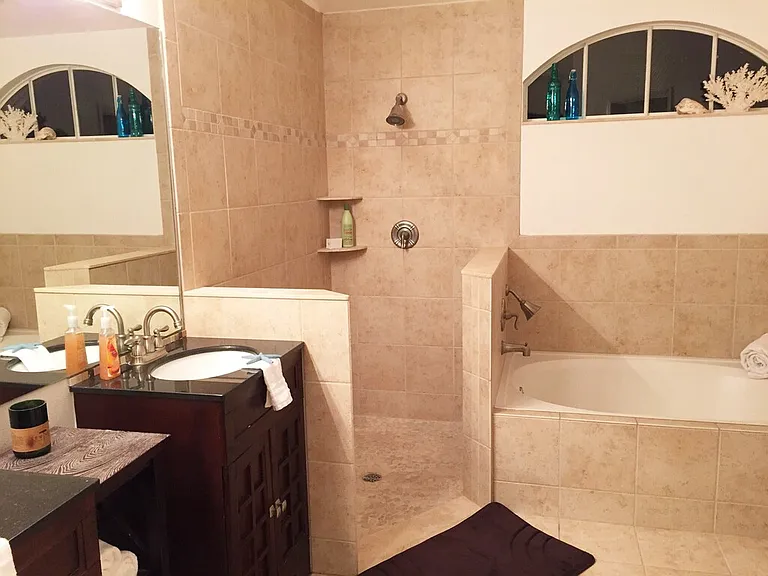 Master bathroom with dual sink vanities, open Roman shower with pebble tile floor and garden tub, large walk in closet and separate toilet room.