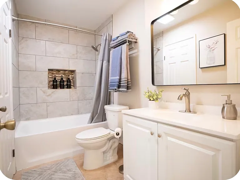 Remodeled bathroom with new shower tile, toilet and cabinet with mirror.