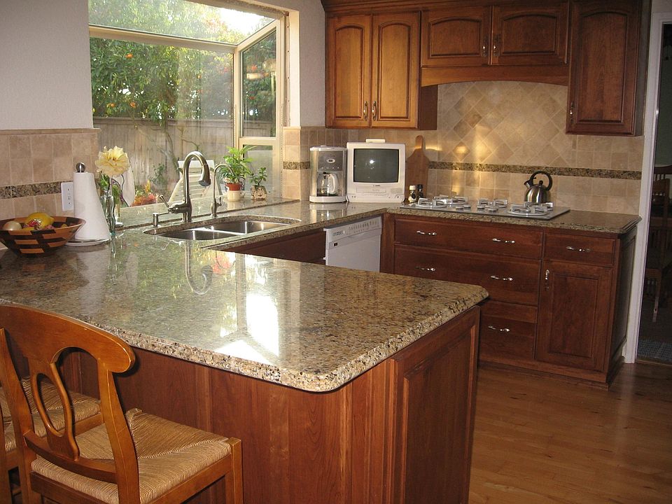 Tastefully remodeled kitchen with high end cherry cabinets, soft close drawers, granite countertops with bar, travertine tile backsplash with granite insert, new bay window