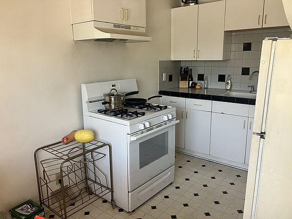 tiled kitchen counters, with stove and refrigerator provided