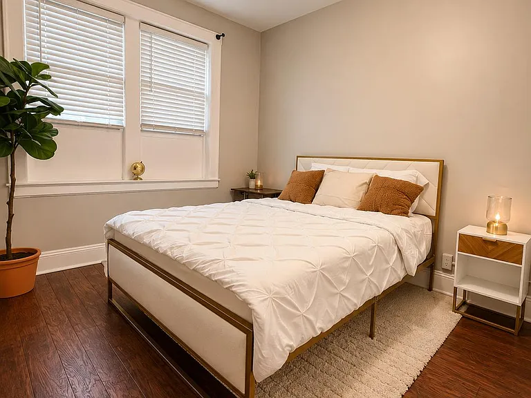 Well-appointed bedroom with a comfortable bed, nightstands, and a large window with blinds for light and privacy.