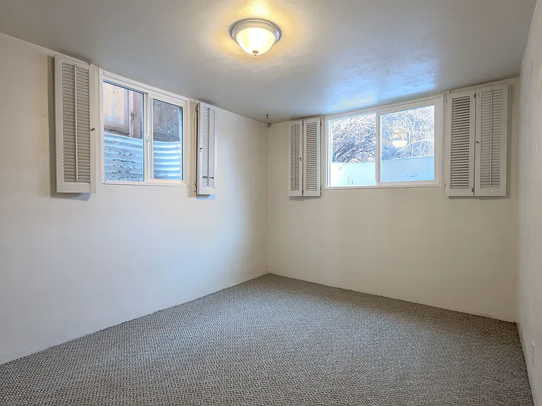 Second garden level bedroom, larger of the two. Lots of light, looks into back yard. Egress windows with shutters for privacy.