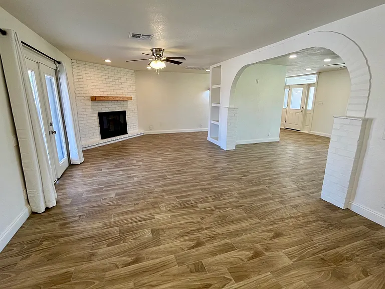 Dining and living area with wood burning fireplace and wood mantel. Ceiling fans