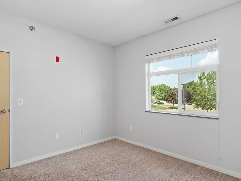 Bright and airy room featuring fresh carpeting, a large window with a serene view, and neutral walls. Bright and airy room featuring fresh carpeting, a large window with a serene view, and neutral walls.