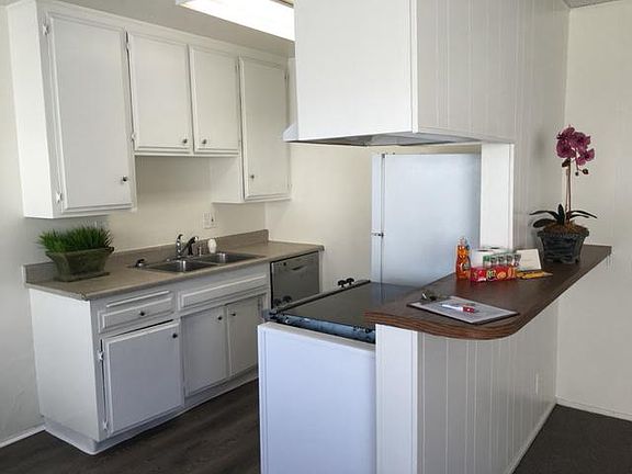 White kitchen with stainless steel dishwasher, stove and fri
