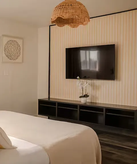 Bright, cozy master bedroom with a king-sized bed, green velvet headboard, soft bedding, natural light, and a crib, making it perfect for both parents and little ones.