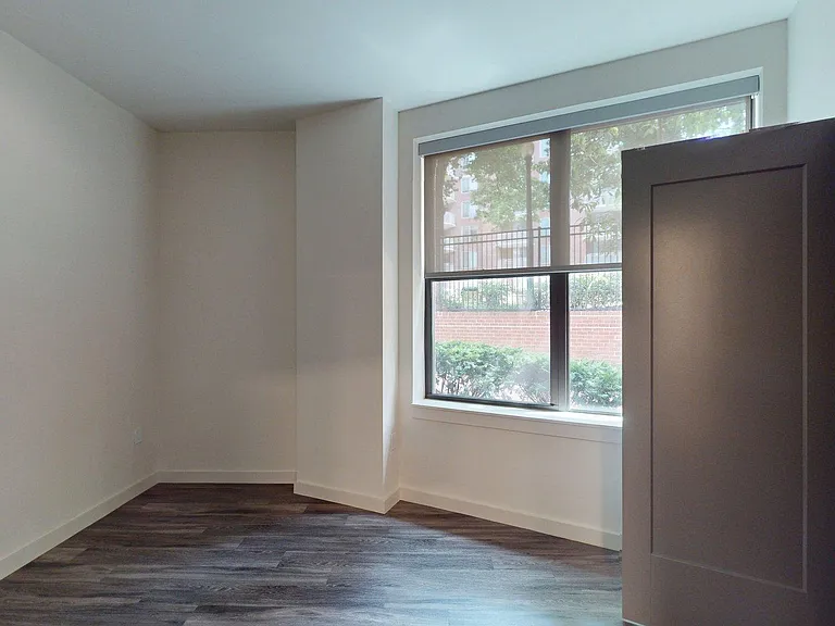 Spacious apartment bedroom with large closet and wood-style flooring.