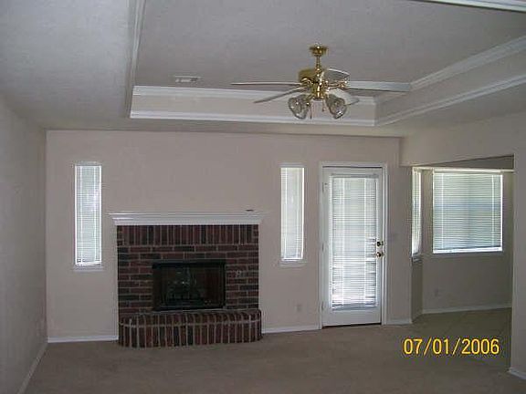 Living room with fireplace, recessed ceiling and fan.