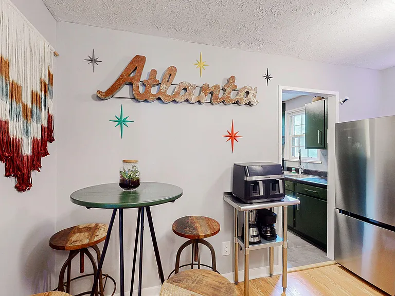 Eat-in kitchen nook with a bistro table, seating, and quick access to the sink, cabinets, and full-size refrigerator.