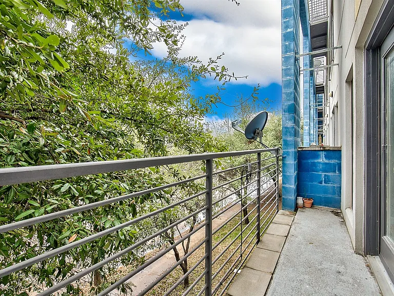 Balcony featuring a metal railing, concrete flooring, exterior wall with blue-painted block, and an exterior door