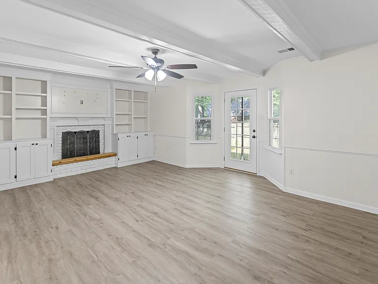 Inviting living room with wood-burning fireplace, built-in shelves, coffered ceiling, and French doors to the backyard.