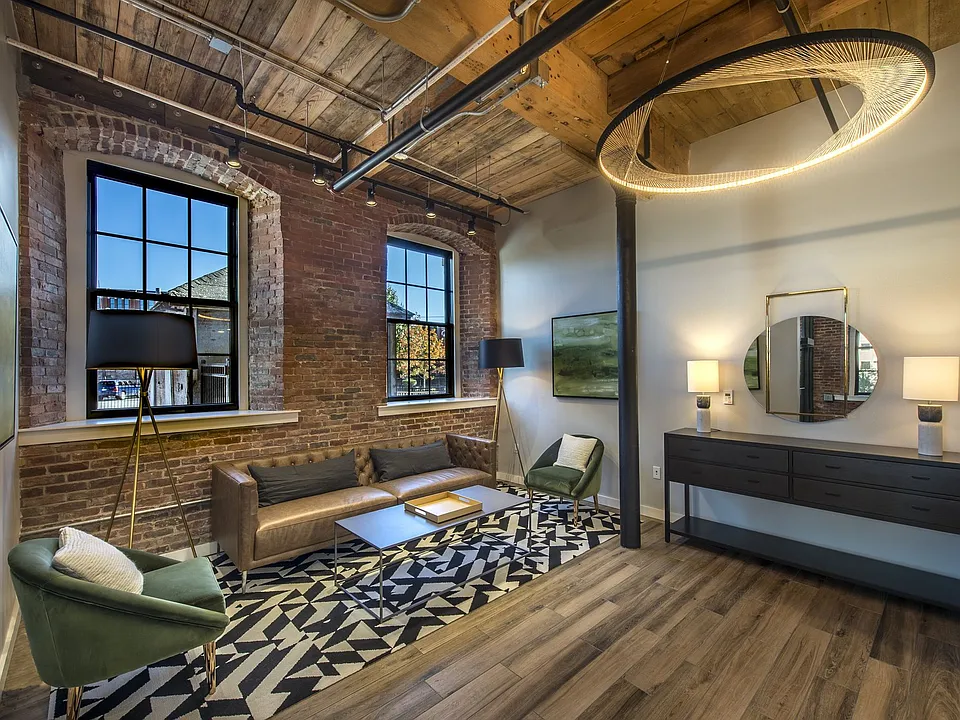 Industrial-style resident lounge with fireplace, exposed beams, and gathering areas