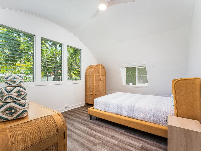 Bedroom 2 featuring vaulted ceilings, luxury vinyl flooring, and windows overlooking the landscaped backyard.