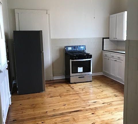 Kitchen view from living room doorway. Stainless steel refrigerator and gas range. Newly refinished wood floors.